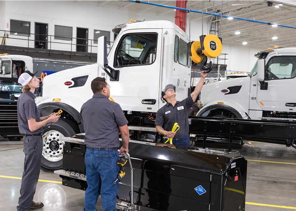 Three Custom Vehicle Solutions Technician attaching CNG Fuel tank to lift hook