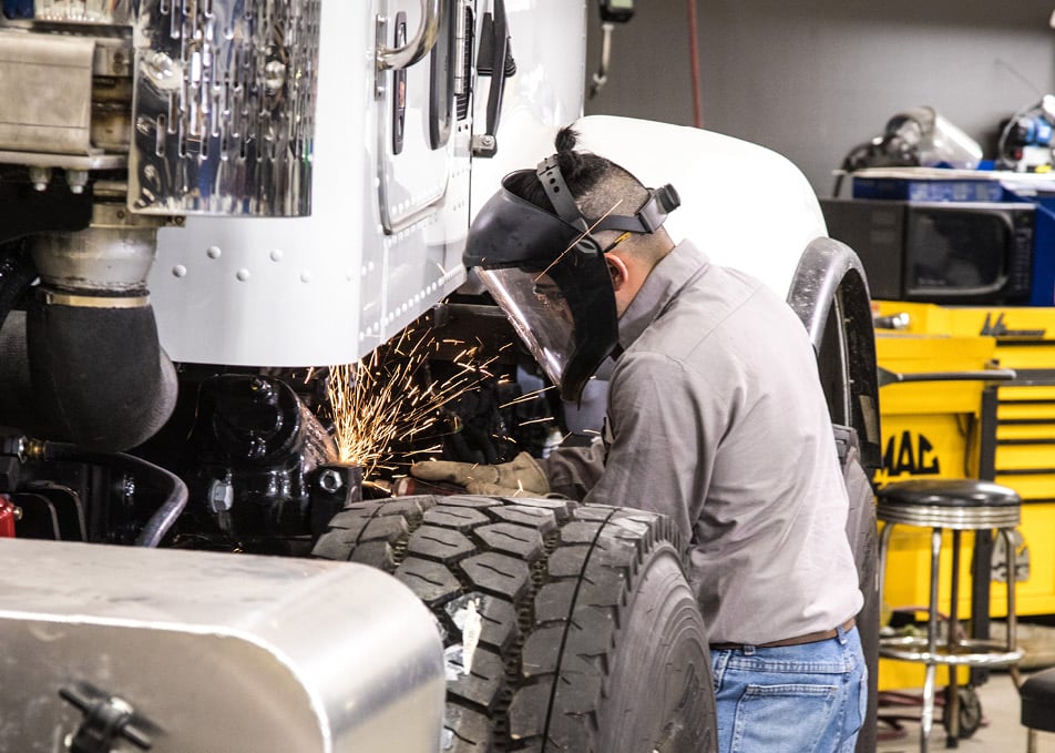Technician welding truck axle