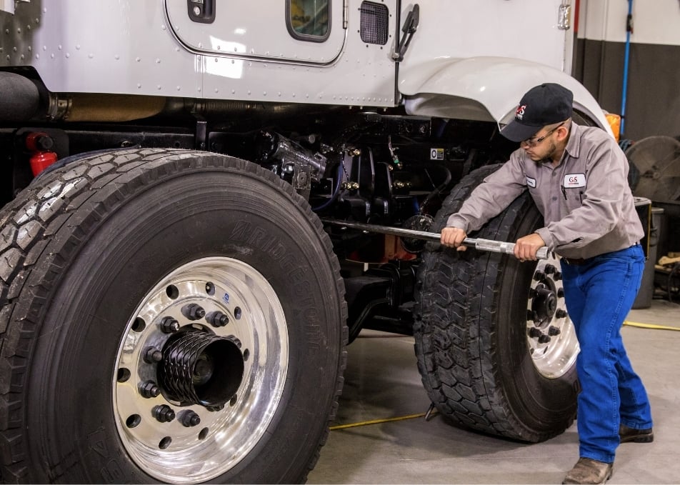Technician tightening truck axle with long tool