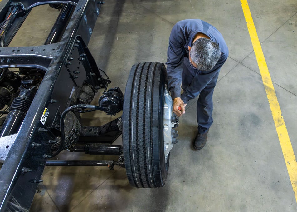 Aerial view of technian installling wheel on truck axle