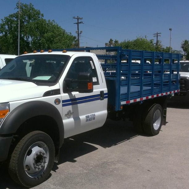 Blue stake bed truck from the front