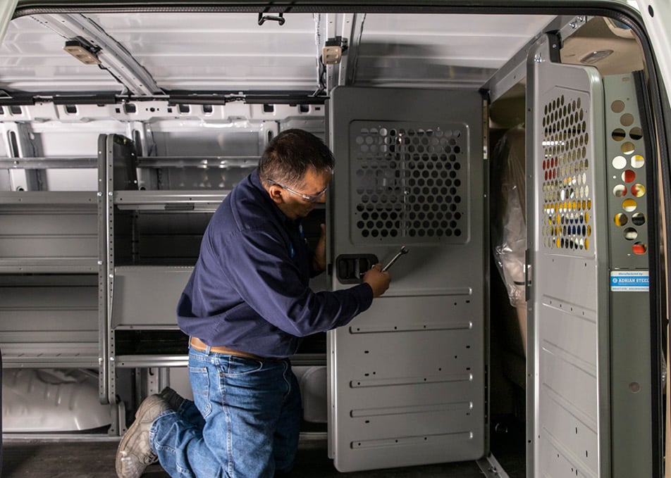 Technician working on cabinet door inside cargo van