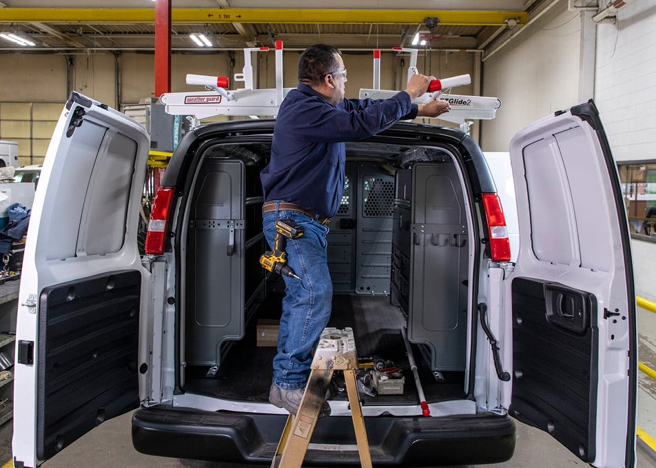 Technician installing roof rack on cargo van