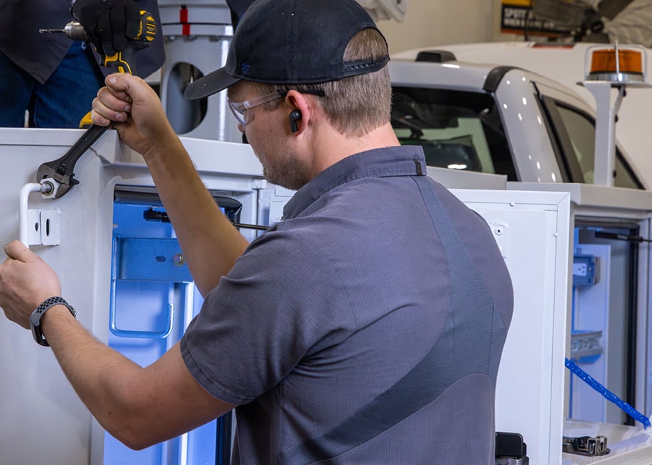 Technician isntalling service body on truck