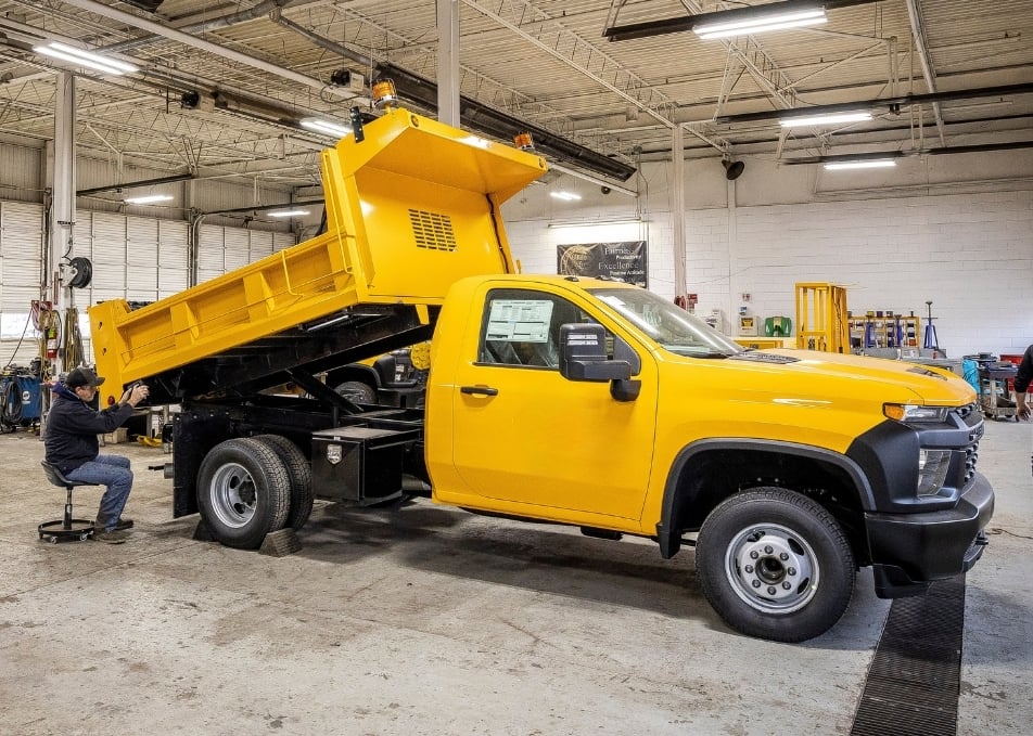 Technician working on installing yellow dump body on truck