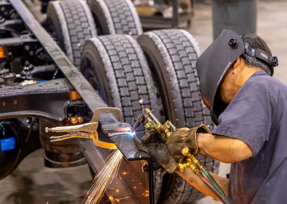 Technician welding two pieces of truck frame together