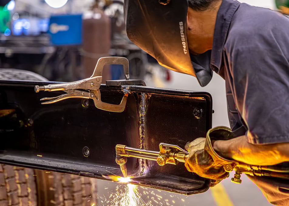 Close up of technician welding two pieces of truck frame together
