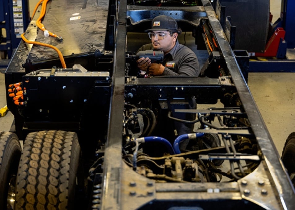 Technician installing cabling and screws to truck frame