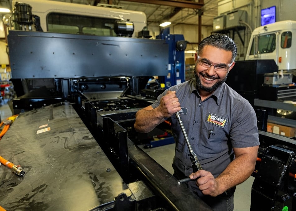 Smiling technician tightening bolt on truck frame