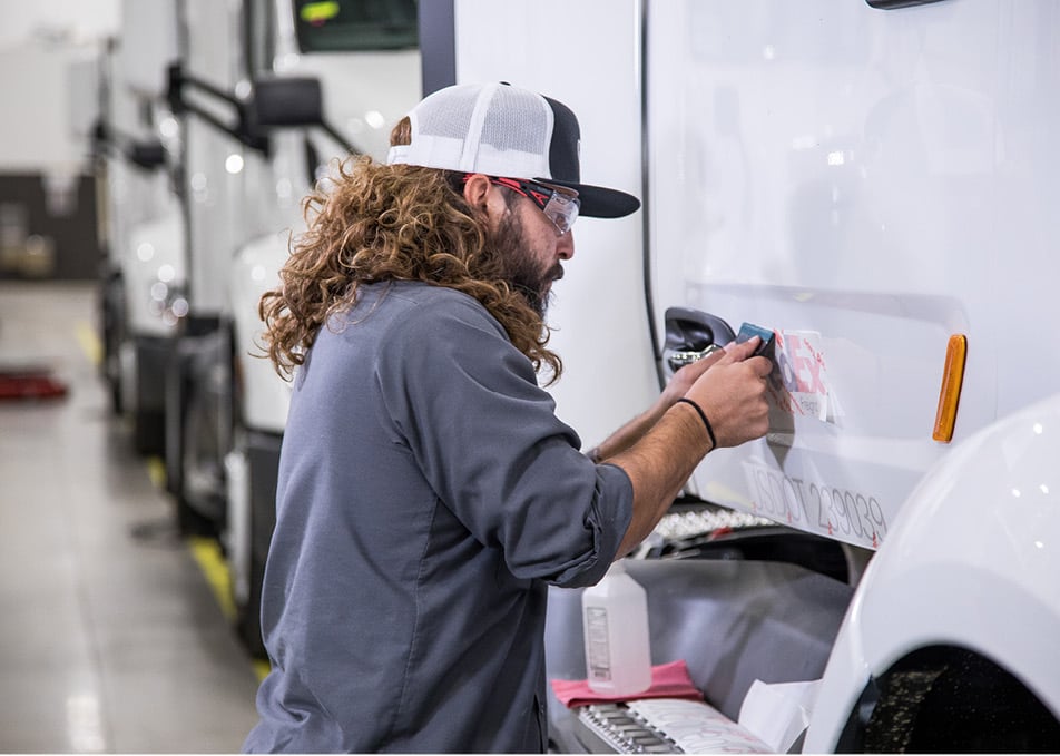 Close up of technician applying vinyl graphic applique to truck door