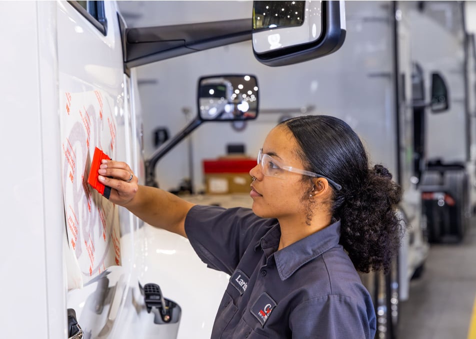 Technician applying vinyl graphic applique of Dr. Pepper logo to truck door