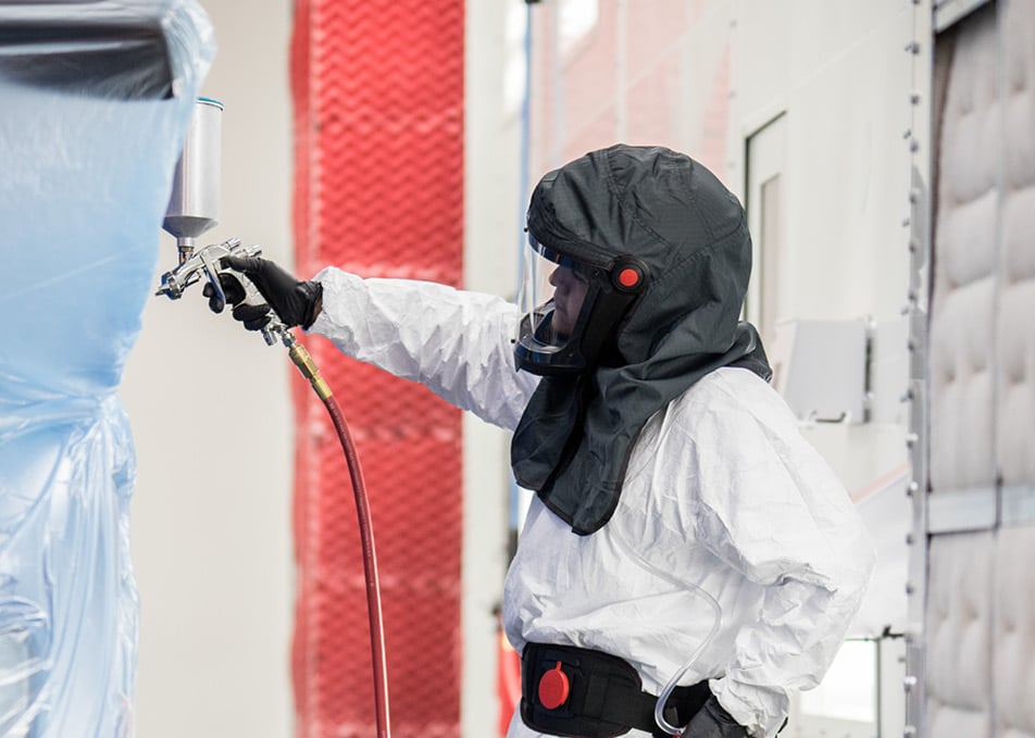 Close up of techician using spray gun to paint part of a semi truck