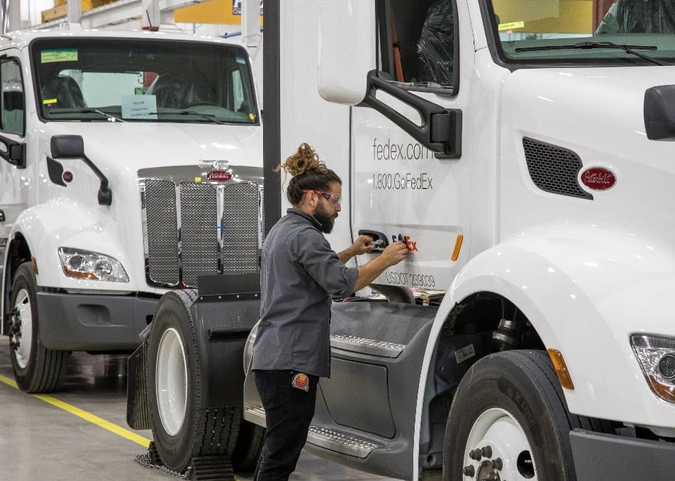Technician installing custom FedEx vinyl graphics to FedEx truck door