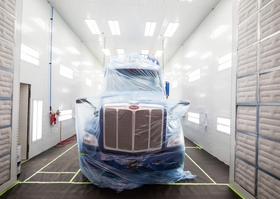 Peterbilt semi truck wrapped in plastic inside paint booth
