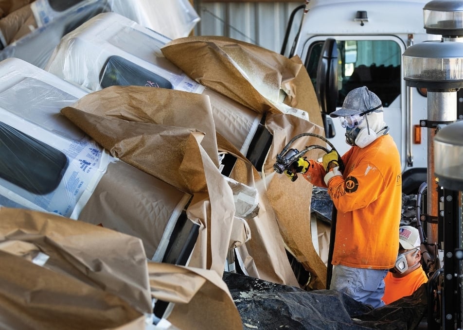 Technician spray painting truck cabs white outdoors