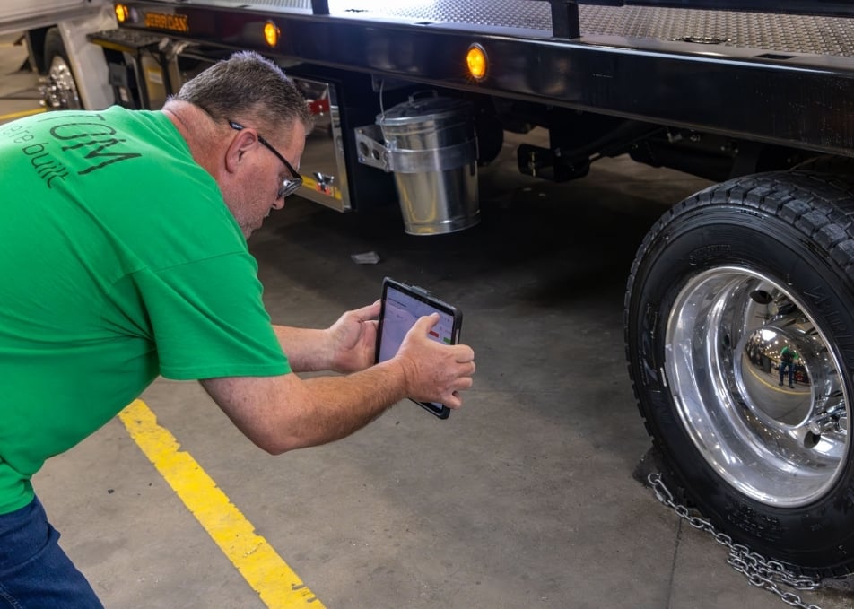 Employee taking photo of truck wheel on tablet