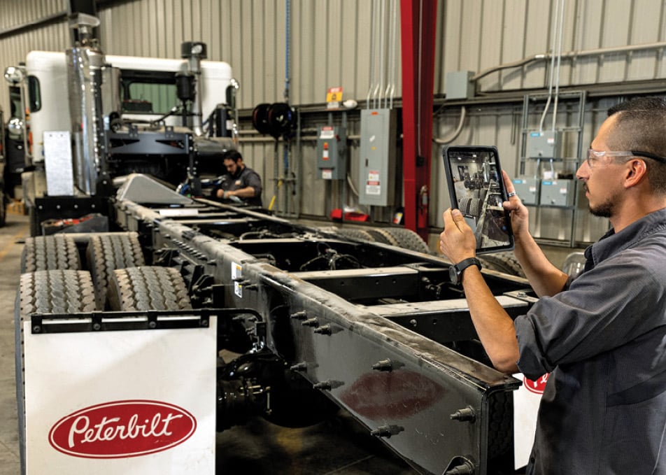 Technician taking photo of Peterbilt truck chassis on tablet