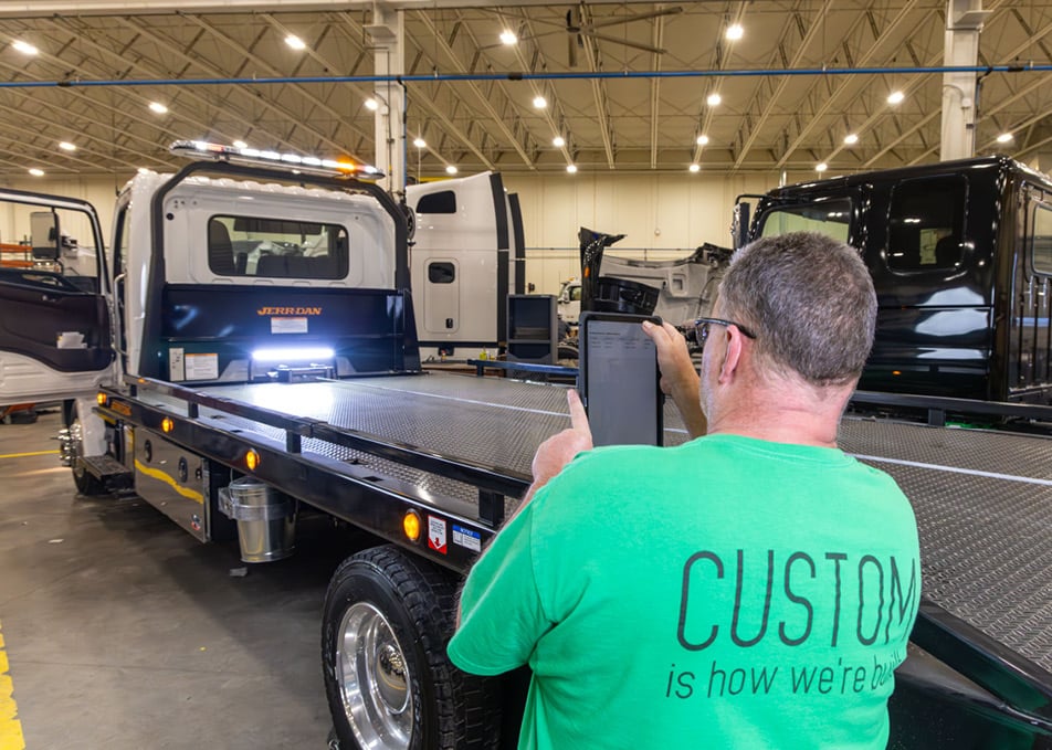 Employee taking photo of flatbed truck on tablet