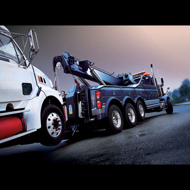 Blue tow truck towing semi truck