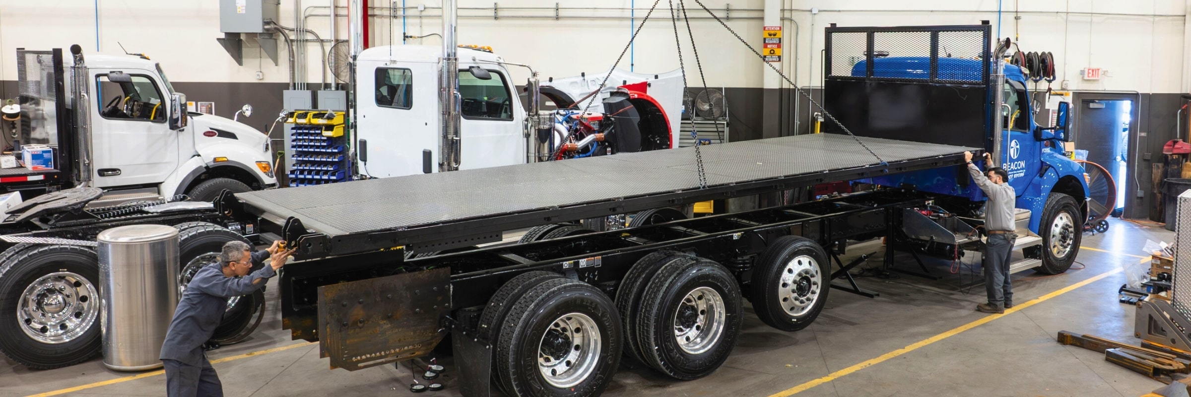 Two Custom Vehicle Solutions technicians installing flatbed body on truck