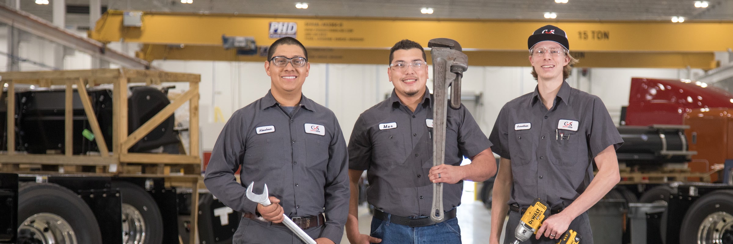 Three Custom Vehicle Solutions technicians smiling and holding tools