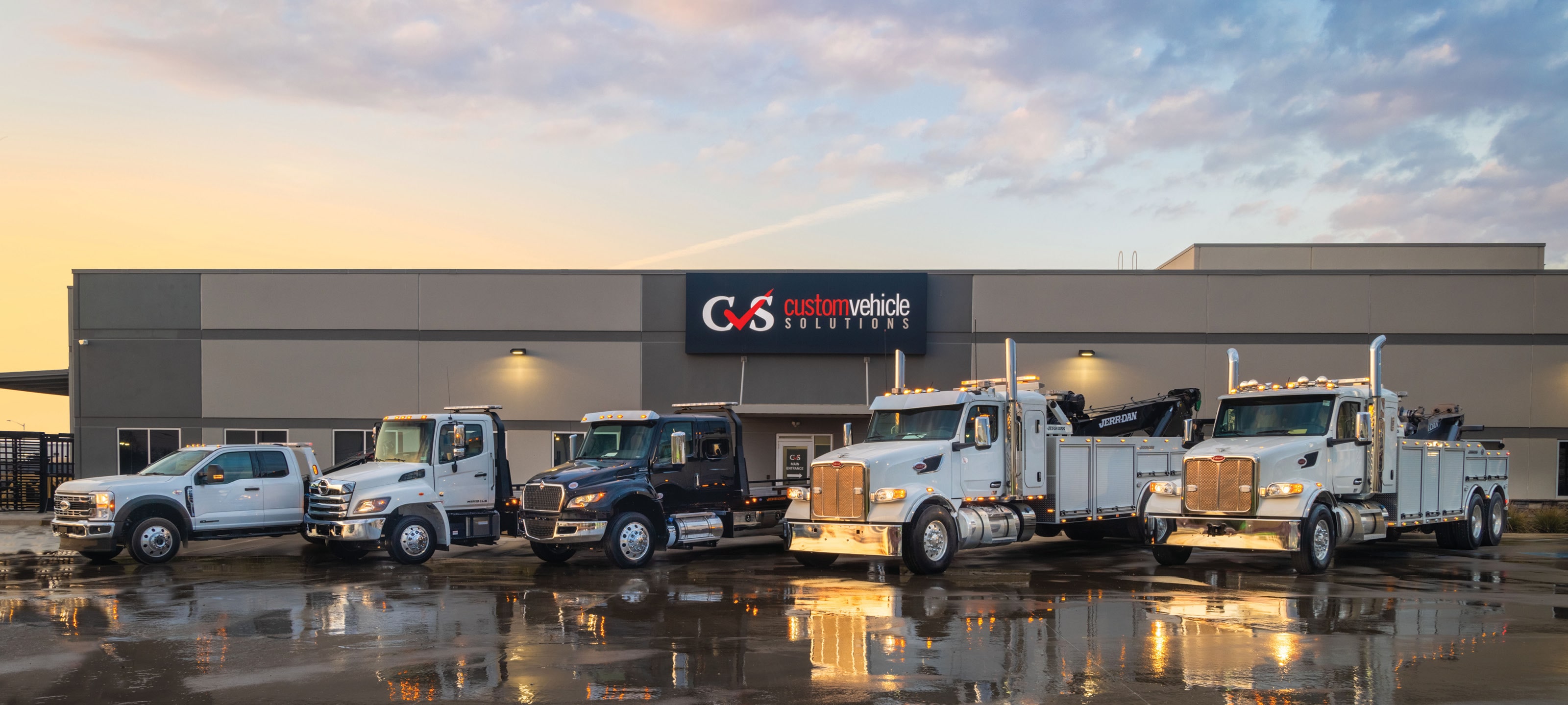 Line up of carrier and wrecker tow trucks outside Custom Vehicle Solutions