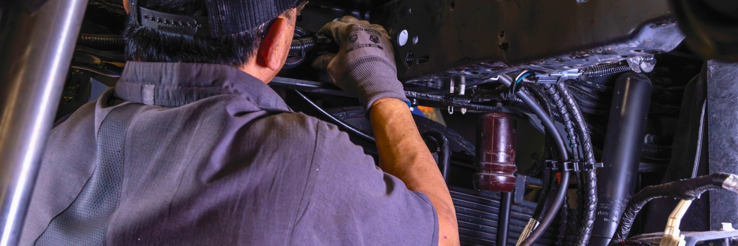 Technician working on hydraulics underneath truck